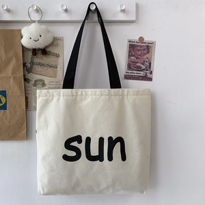 Detail of minimalist cream canvas tote bag with black sun print and woven handles