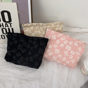 Detailed view of three cosmetic bags with 3D floral texture in black, pink and beige colors