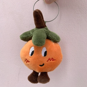 Close-up of cute plush orange fruit keychain with embroidered smiling face and legs