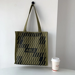 Detail of army green canvas tote bag featuring geometric patterns and ABLE lettering
