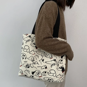 Detail of canvas tote bag with black strap showing minimalist dog illustrations