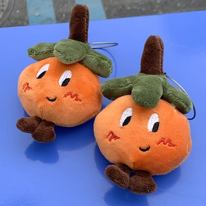 Close-up of two cute orange plush pendants with detailed embroidery and steel rings