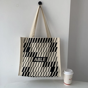 Detail of a large canvas tote bag with black geometric patterns and ABLE lettering on white