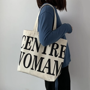 Detail of the minimalist white canvas tote bag featuring large black CENTRE WOMAN lettering
