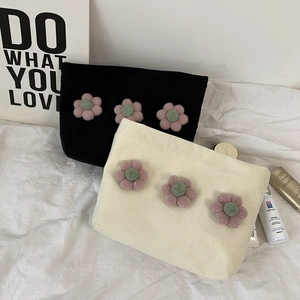 Detail of canvas makeup bags featuring 3D plush flowers and a secure zipper closure