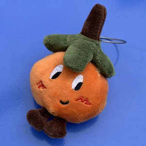Close-up of cute plush orange charm featuring embroidery details and silver metal ring