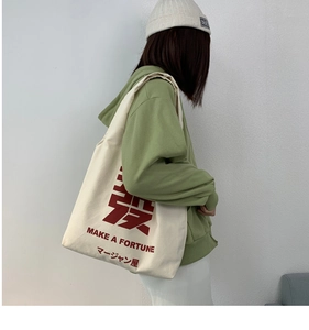 Detail of canvas tote bag featuring red text print and large capacity over the shoulder