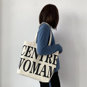 Detailed view of large canvas tote bag with bold CENTRE WOMAN lettering and wide shoulder strap