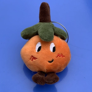 Macro shot of cute plush orange pumpkin pendant with green leaves and a metal ring