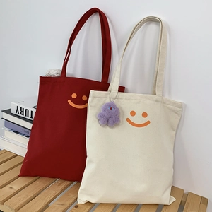 Detail of canvas tote bags with orange smiley faces and a purple plush octopus charm