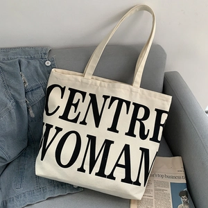 Detail of off-white canvas tote bag with black text against a casual sofa background