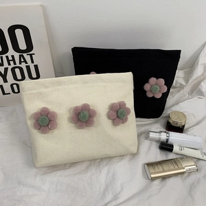 Detail view of canvas makeup bags featuring 3D plush flowers in white and black