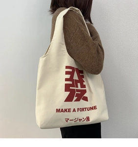 Detail of canvas tote bag featuring red Mahjong character print and shoulder strap