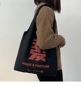 Detail of black canvas tote bag featuring red Mahjong print and MAKE A FORTUNE text
