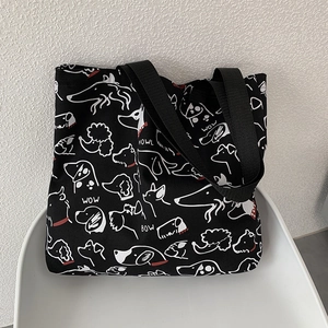 Detail of hand-drawn dog print on black canvas tote bag with sturdy woven straps