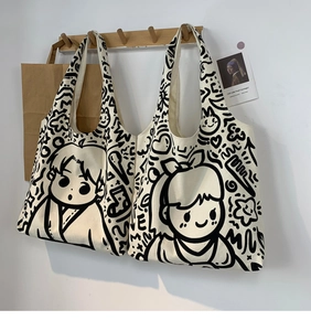 Detail view of two canvas tote bags with cute black and white cartoon graffiti illustrations