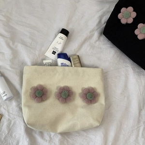 Detailed view of canvas makeup bag with 3D yarn flowers storing skincare essentials