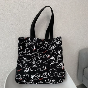 Detail of black canvas tote bag with white dog illustrations and cute bow-wow text