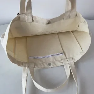 Detail view of the canvas tote bag showing the magnetic snap closure and zippered inner pocket