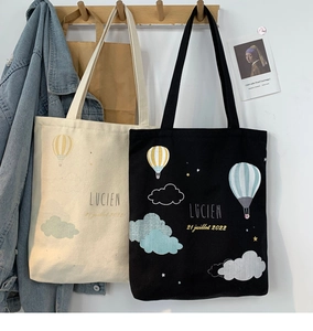 Detail of minimalist canvas tote bags with balloon prints in black and cream white colors