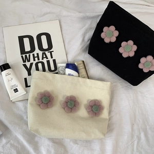 Detail of floral canvas makeup bag with 3D wool flowers for organizing cosmetics