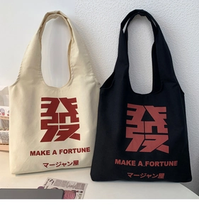 Detail of canvas tote bags in cream and black colors with red Mahjong character print