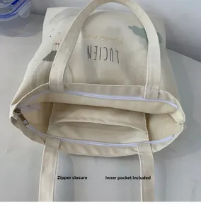 Detail view of the canvas tote bag showing the secure white zipper and internal open pocket