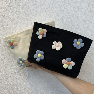 Detail of floral canvas makeup bags in black and beige with 3D colorful petal patches