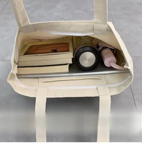 Top view of cream canvas tote bag showing spacious interior with books and a laptop
