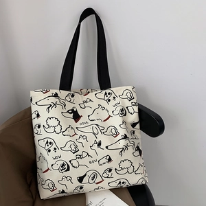 Detailed view of canvas tote bag with black dog illustrations and sturdy woven handles