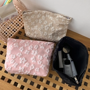 Close-up of floral jacquard cosmetic bags in beige, pink, and black colors