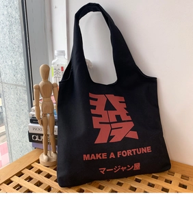 Close-up of black canvas tote bag featuring red oriental typography and fortune text