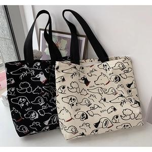 Detail of canvas tote bags featuring artistic dog line art prints and wide nylon handles