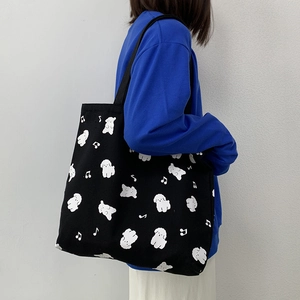 Détail du grand sac cabas en toile noire avec imprimé de petits chiens blancs mignons