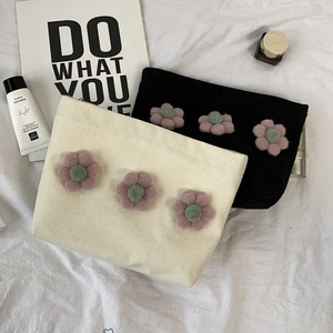Detail shot of canvas cosmetic bags featuring three-dimensional plush floral decorations