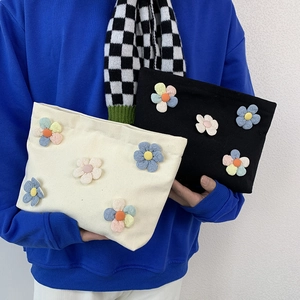 Detail of floral canvas makeup bags with 3D fabric flowers in black and beige colors