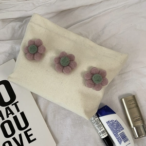 Detail of canvas makeup bag with 3D floral accents and sturdy zipper closure