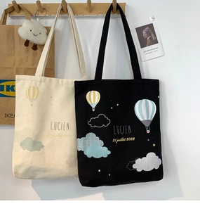 Close-up of black and white canvas tote bags with hot air balloon prints on a rack