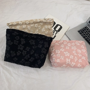Detailed view of jacquard makeup bags with 3D floral textures in black, beige and pink