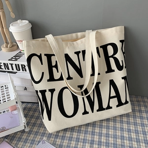 Detail of Century Woman text print on cream canvas tote bag with shoulder straps