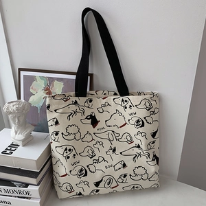 Detail of canvas tote bag featuring minimalist dog sketches and sturdy black handles