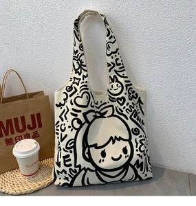 Detailed view of cream canvas tote bag with black artistic graffiti and large capacity