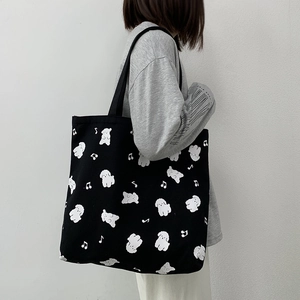 Détail d'un sac cabas en toile noire avec des motifs de chiots blancs mignons