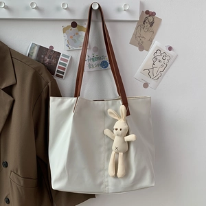 Minimalist canvas tote bag with brown straps and a cute plush rabbit pendant detail