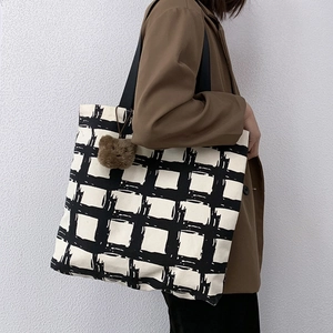 Detail of canvas tote with grid pattern and cute teddy bear charm on shoulder