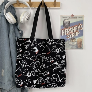 Detailed close-up of a black canvas tote bag with dog illustrations hanging on a wooden hook