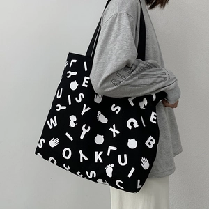 Detail of a large capacity black canvas tote bag with white alphabet and icon prints