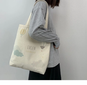 Detail of minimalist canvas tote bag with sun and cloud prints and long shoulder strap