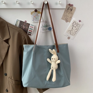 Close-up of Morandi blue tote bag with thin brown straps and a cute plush bunny charm