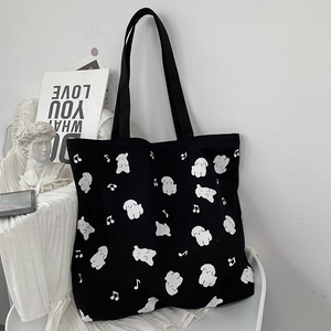 Détail d'un cabas en toile noire avec motifs de caniche blanc et notes de musique